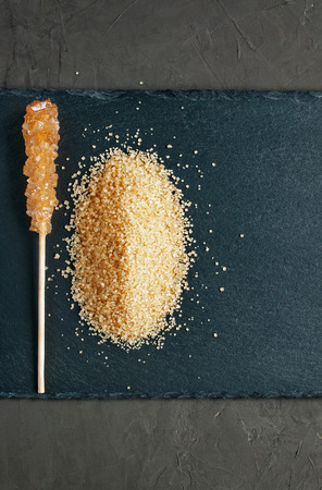 Brown cane sugar on a black slate backgroundの写真素材