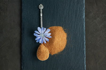 Blue chicory flower and powder of instant chicory on black slate board