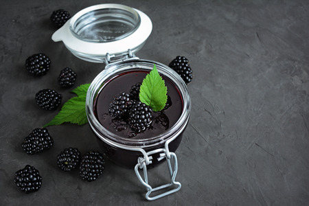 Homemade blackberry jam in a glass jar with fresh berriesの写真素材