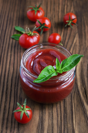 Tomato sauce and basil in glass jar on a wooden backgroundの写真素材