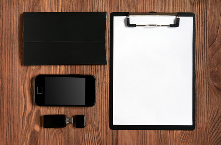 Set of stationery with clipboard, notepad, smartphone and flash driver on wooden background for mock upの写真素材