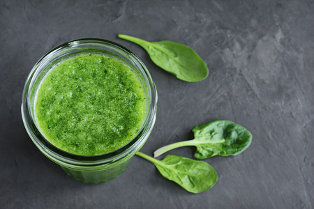 Green smoothie of fresh spinach in a glass jar on black slate board, top view.の写真素材