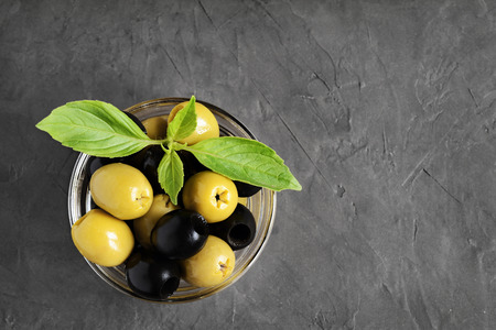 Black and green olives in glass bowl on black concrete backgroundの写真素材