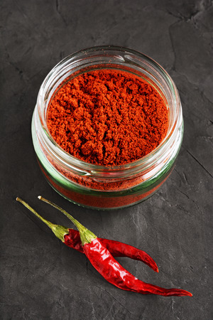Ground red chili pepper and two dried pods on a black backgroundの写真素材