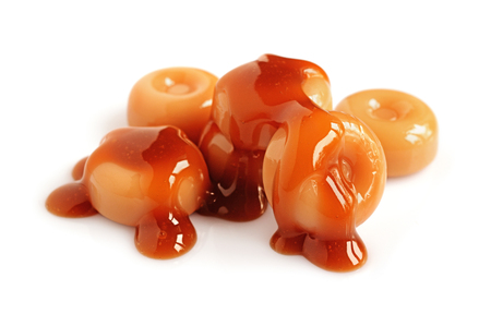 Caramel candies and liquid caramel isolated on whiteの写真素材