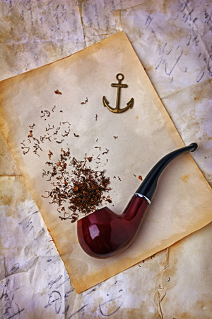Smoking pipe and tobacco on old paper textureの写真素材