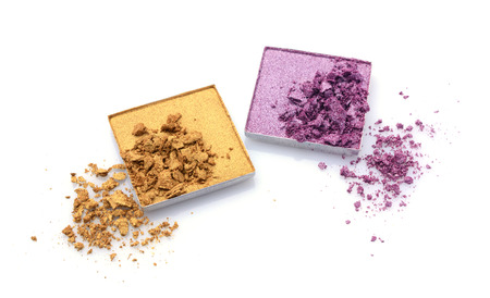 Crushed golden and violet eyeshadows isolated on whiteの写真素材