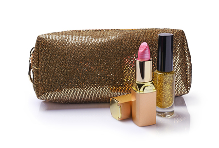 Composition of cosmetics with gold nail polish, pink lipstick, and golden cosmetic bag isolated on whiteの写真素材