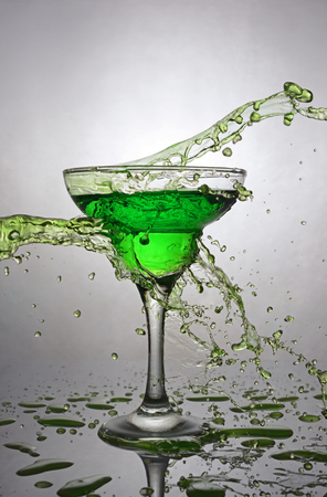Splash in glass of green alcoholic cocktail drink on gray gradient backgroundの写真素材