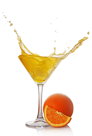 Splash in glass of yellow alcoholic cocktail drink with orange isolated on white backgroundの写真素材