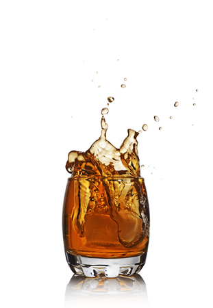 Splash in glass of scotch whiskey with ice cube isolated on white backgroundの写真素材