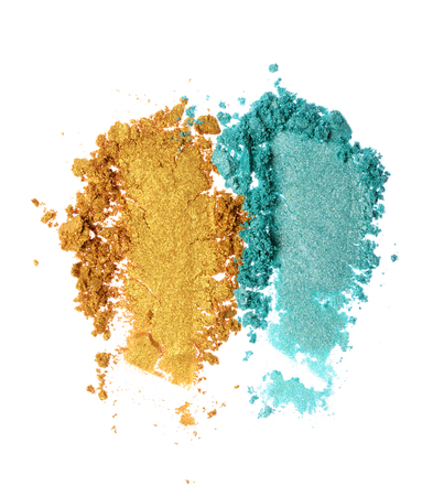 Smears of crushed teal and golden shiny eyeshadow as sample of cosmetic product isolated on white backgroundの写真素材