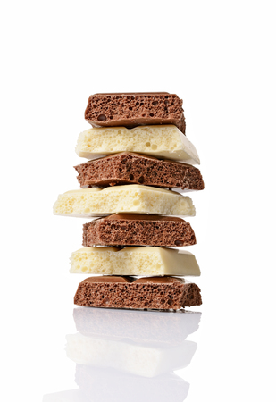 Close-up pieces of porous white and milk chocolate bars isolated on white backgroundの写真素材