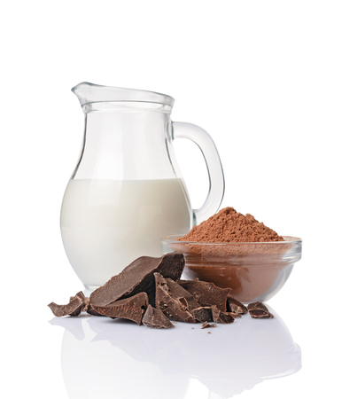 Close-up pieces of chunk black chocolate with glass bowl of cocoa powder and jug of milk isolated on white backgroundの写真素材