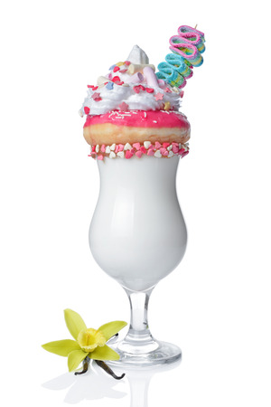 Crazy vanilla milk shake with pink donut, whipped cream, sprinkles, marshmallows and colored candy in glass isolated on white backgroundの写真素材