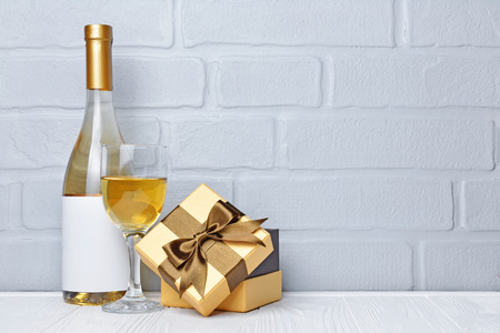 White wine bottle with empty label, glass for tasting and gift box for romantic surprise on gray brick wall backgroundの写真素材