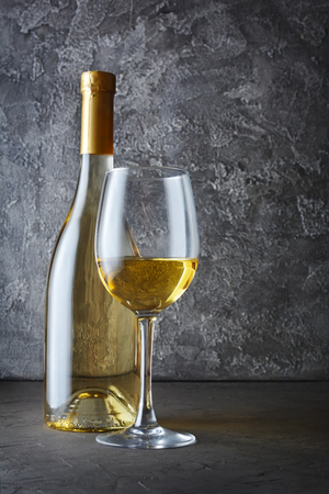 White wine bottle and glass for tasting in dark cellar on gray concrete backgroundの写真素材