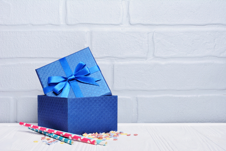 Blue classic gift box with satin bow and cocktail straws with sprinkles as attributes of party on gray brick wall backgroundの写真素材