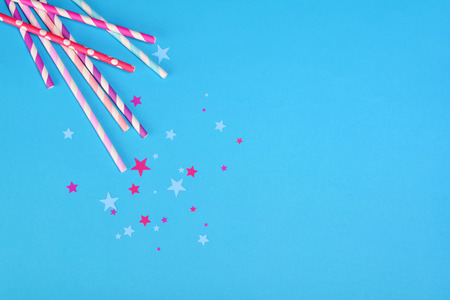 Colorful cocktail straws with confetti in the shape of stars as attributes of party on blue backgroundの写真素材