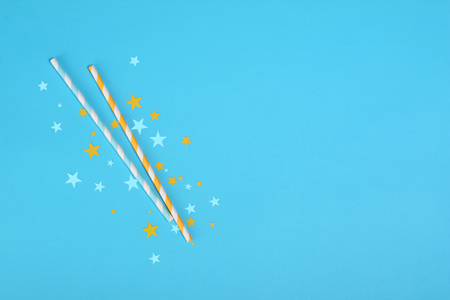 Colorful paper striped cocktail straws with confetti in the shape of stars as attributes of party on blue backgroundの写真素材