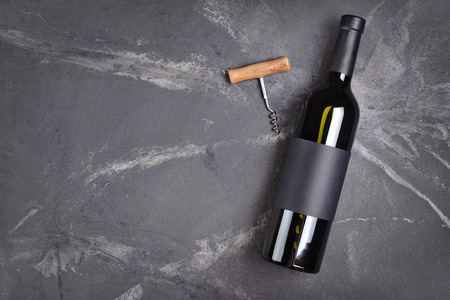 Flat lay of lying wine bottle with black empty label for tasting and copy space on dark marble backgroundの写真素材
