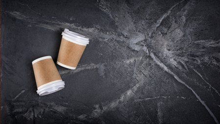 Top view of disposable take-out mockup white paper coffee cups with kraft brown holder on black marble background with copy spaceの写真素材