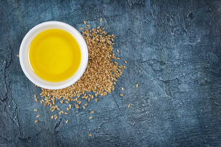Top view of linseed oil in white bowl and flax seeds on blue concrete background with copy spaceの写真素材