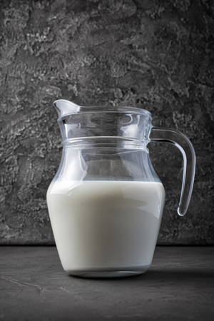 Healthy natural cow milk in glass jug on dark gray concrete backgroundの写真素材