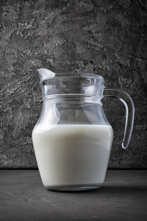 Healthy natural cow milk in glass jug on dark gray concrete backgroundの写真素材