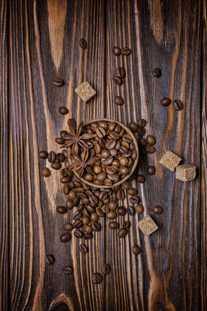 Top view of roasted coffee beans, cane sugar and anise stars for morning espresso on rustic wooden backgroundの写真素材