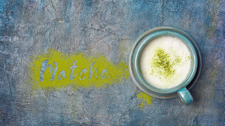 Top view on lettering from organic green matcha tea powder with popular healthy latte on blue concrete backgroundの写真素材