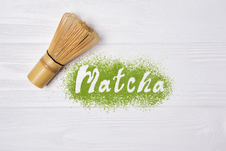 Top view on lettering from organic green matcha tea powder with bamboo chasen on white wooden backgroundの写真素材