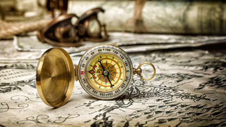 Closeup view of a vintage golden compass on an old retro map backgroundの写真素材