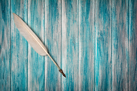 Top view on old vintage quill pen on blue wooden background with copy spaceの写真素材