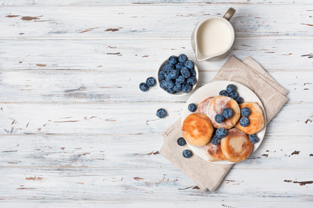 Tasty cottage cheese pancakes with blueberries and milk jug on rustic wooden background with copy spaceの写真素材