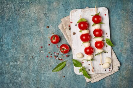 Top view of small balls mozzarella cheese and Cherry tomatoes with basil leaves as ingredients for...