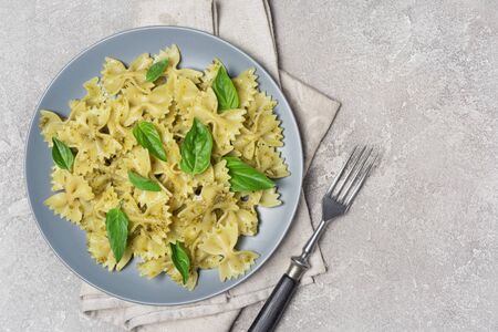 Top view of tasty farfalle pasta with pesto sauce and basil leaves on gray concrete background with copy spaceの写真素材