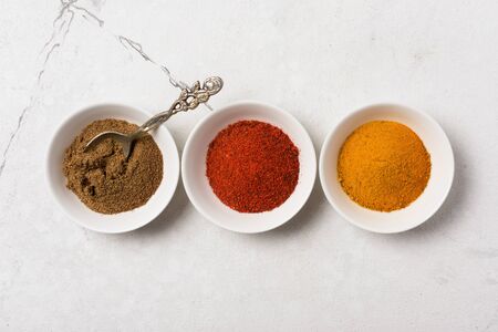 Top view of bright ground spices in white bowl for aromatic food on marble backgroundの写真素材