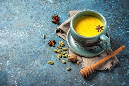 Golden turmeric milk in big cozy cup for healthy life on blue concrete background with copy spaceの写真素材