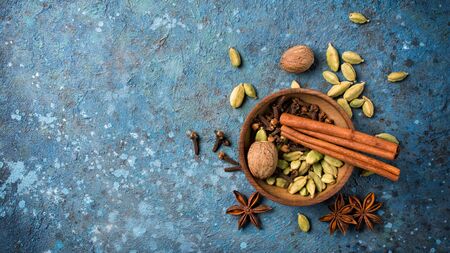 Top view of spices in wooden bowl for mulled wine or masala tea on blue concrete background with copy spaceの写真素材
