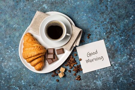 Top view of traditional french breakfast with chocolate croissant and coffee on blue concrete background with copy spaceの写真素材