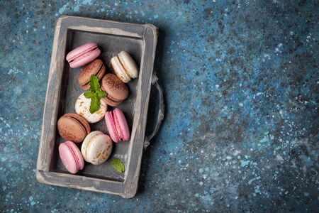 Top view of french dessert tasty macaroons with fresh mint on blue concrete background with copy spaceの写真素材