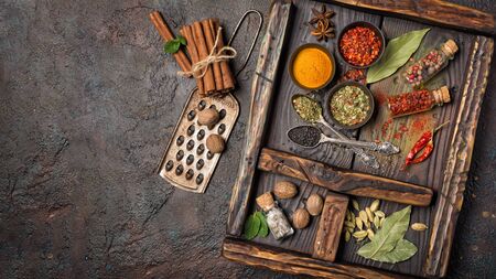 Top view of mix bright spices and herbs in small bowls and bottles as ingredient for healthy food on brown grunge background with copy spaceの写真素材