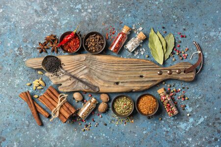 Top view of mix bright spices and herbs in small bowls and bottles as ingredient for healthy food on blue concrete backgroundの写真素材