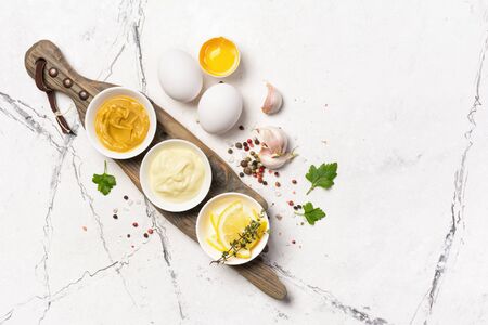 Top view of ingredients for homemade mayonnaise as mustard, eggs, spices on white marble backgroundの写真素材