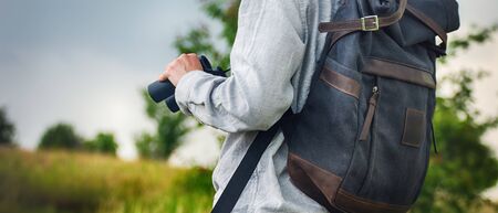 Young adult in shirt with gray backpack holding a binocular for looking around or bird watching. Travel conceptの写真素材