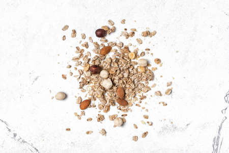 Top view of oatmeal or granola with almond and hazelnut for nutritious breakfast on white marble backgroundの写真素材