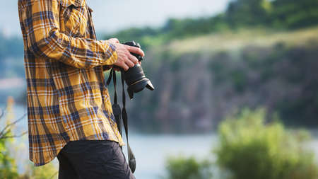 Young adult in shirt holding a camera for landscape photography. Travel conceptの写真素材