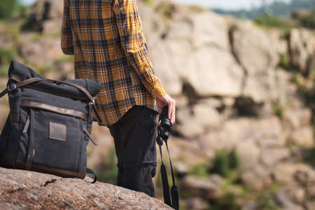 Young adult in shirt with gray backpack holding a binocular for looking around or bird watching. Travel conceptの写真素材