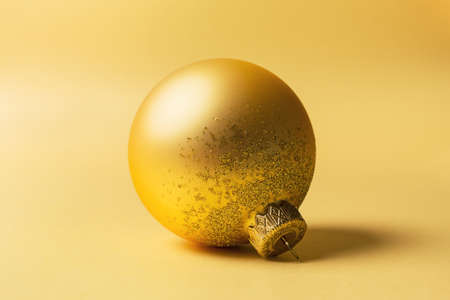 Christmas or New Year decoration. Closeup of beautiful shiny golden christmas ball on gold backgroundの写真素材